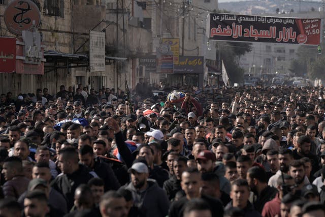 Mourners carry the bodies of eight Palestinians, some draped in the flag of the Islamic Jihad militant group, during a joint funeral in Jenin on Thursday January 26 2023