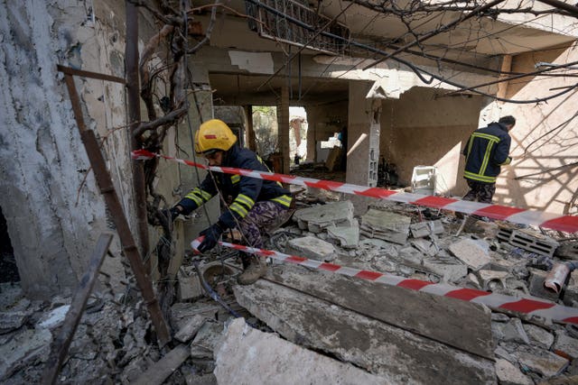 Palestinian rescuers inspect the site of a damaged building following an Israeli forces raid in the West Bank city of Jenin