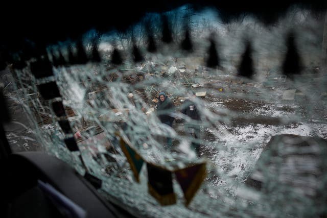 Men are seen through a smashed window of a damaged truck following a rocket attack in Kyiv