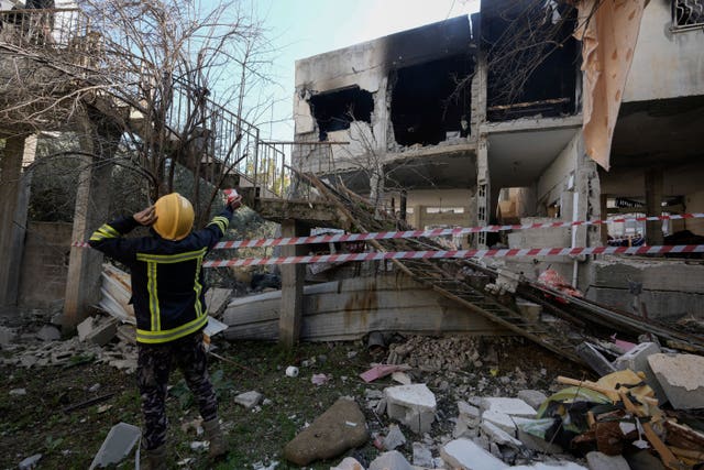 Palestinian rescuers inspect the site of a damaged building following an Israeli forces raid in the West Bank city of Jenin 