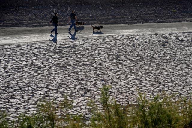 People walk by cracked earth in an area once under the water of Lake Mead at the Lake Mead National Recreation Area, near Boulder City, Nevada