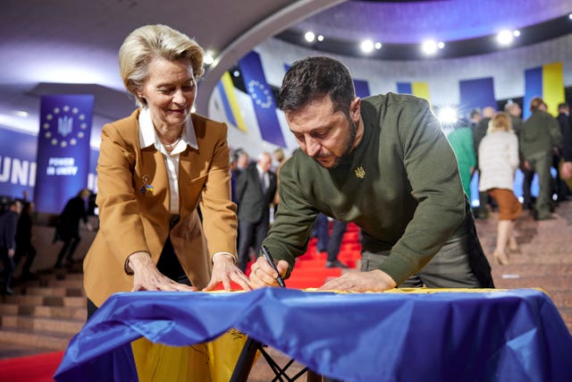 Ukrainian President Volodymyr Zelensky, right, and European Commission president Ursula von der Leyen write their wishes on a Ukrainian flag during the EU-Ukraine summit in Kyiv on Thursday February 2 2023
