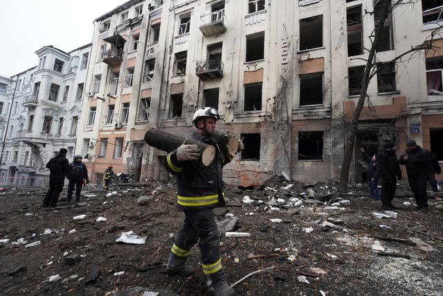 An emergency worker carries pieces of a sawn tree in front of a residential building which was hit by a Russian rocket at the city centre of Kharkiv, Ukraine