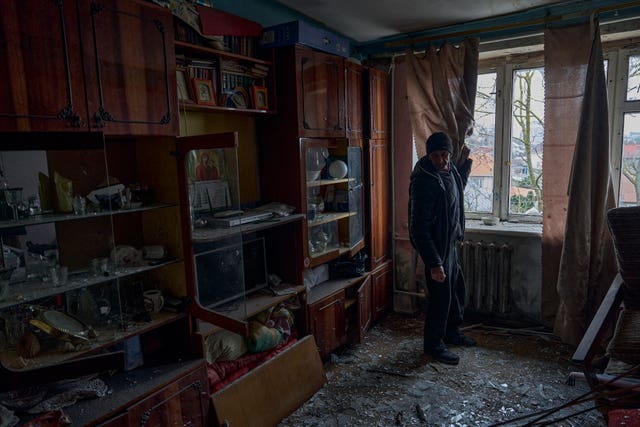 A man looks at shards of glass on his apartment floor after a Russian shelling in Kherson, Ukraine