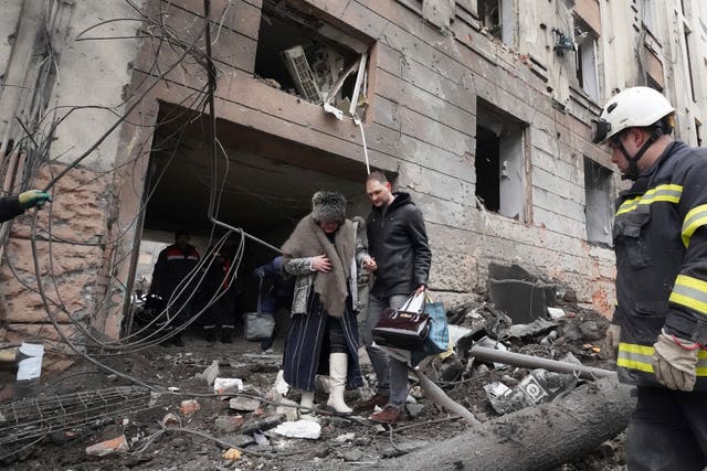 A man helps a woman to walk out from a residential building which was hit by a Russian rocket, in the city centre of Kharkiv, Ukraine