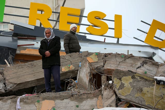 A man prays on a collapsed building in Malatya, Turkey