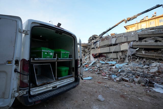 A van with coffins is parked next to a destroyed building in Gaziantep, south-east Turkey