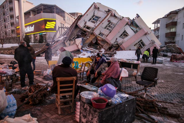 People stand by collapsed buildings in Golbasi, in Adiyaman province, southern Turkey