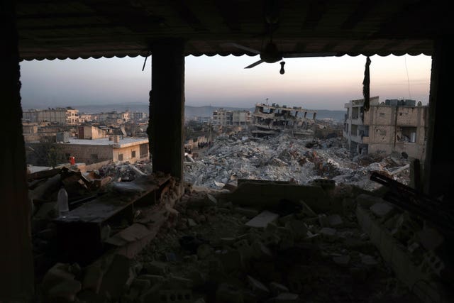 Collapsed buildings are seen through the windows of a damaged house following a devastating earthquake in the town of Jinderis, Aleppo province, Syria 