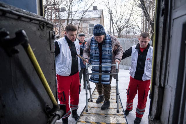 MSF workers help a woman to get inside the MSF medical train that evacuates patients from near the frontlines of the fighting to safer areas at the train station in Pokrovsk, Ukraine