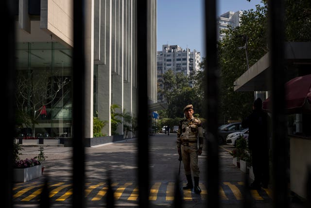 An armed security person stands stand guard at the gate of a building housing BBC office in New Delhi, India