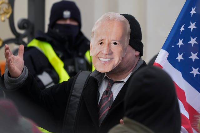 A man wears a face mask of Mr Biden as he waits outside the Presidential Palace in Warsaw