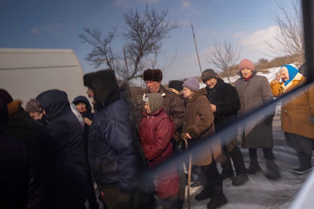 Villagers, reflected in the windows of a van, wait in line to receive humanitarian aid and a medical examination in a mobile clinic in the village of Nechvolodivka, Ukraine