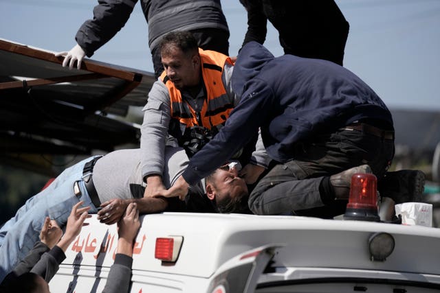An injured Palestinian is lifted on to an ambulance