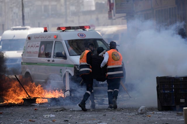 Medics run through tear gas as they evacuate a wounded Palestinian during clashes with Israeli forces