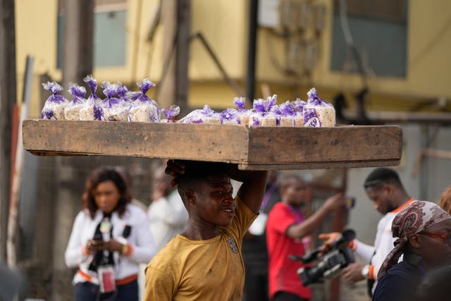 A street vendor carries packets of bread to sell next to a polling station during the presidential elections in Lagos, Nigeria