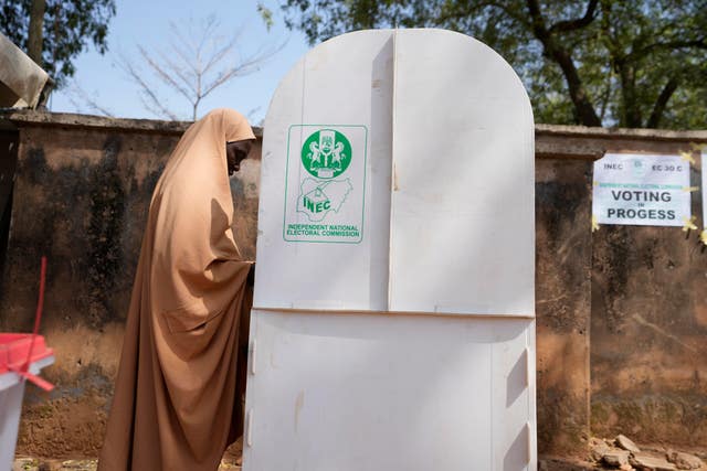 A woman fills her ballot in a booth before casting her vote during the presidential and parliamentary elections in Yola, Nigeria