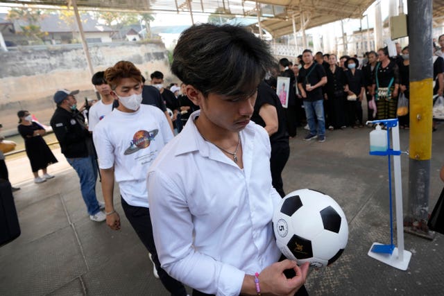 Adul Sam-on, a member of the Wild Boars football team rescued from a flooded cave 2018, gets on a boat with a football as the family members scatter the ashes of Duangphet Phromthep