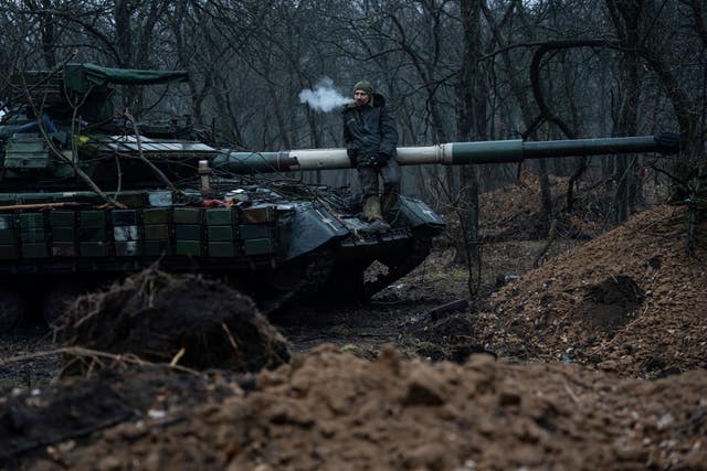 A Ukrainian serviceman smokes a cigarette standing atop a tank near Bakhmut, Ukraine