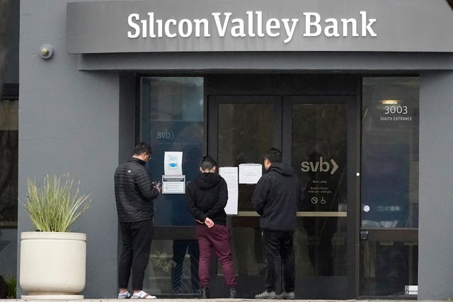 People look at signs posted outside of an entrance to Silicon Valley Bank in Santa Clara, California