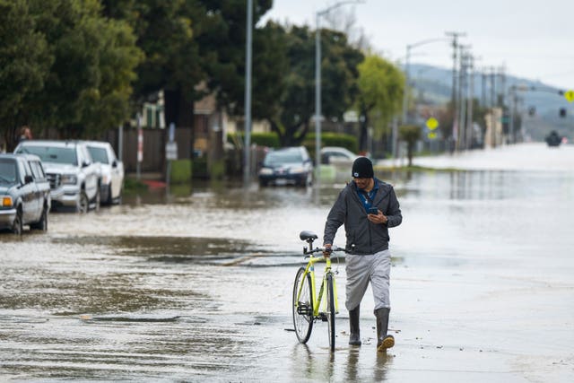 A man with a bicycle amid floodwater