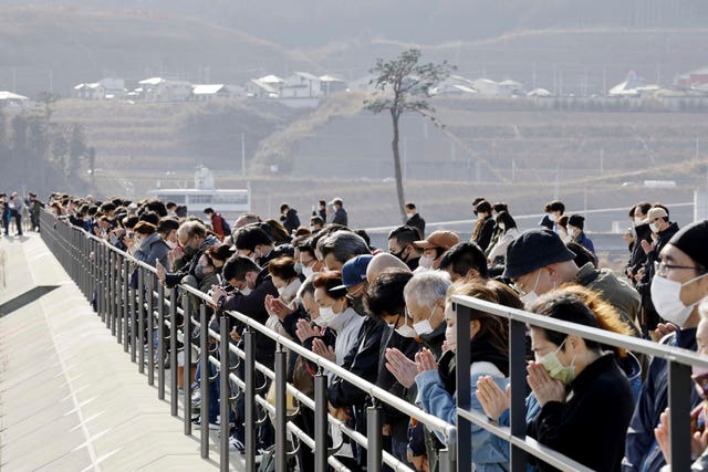 People observe a moment of silence at 2.46pm, the moment the earthquake struck, in Rikuzentakata, Iwate prefecture