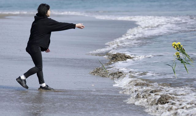 A man throws a flower into the sea in a tribute to the disaster's victims