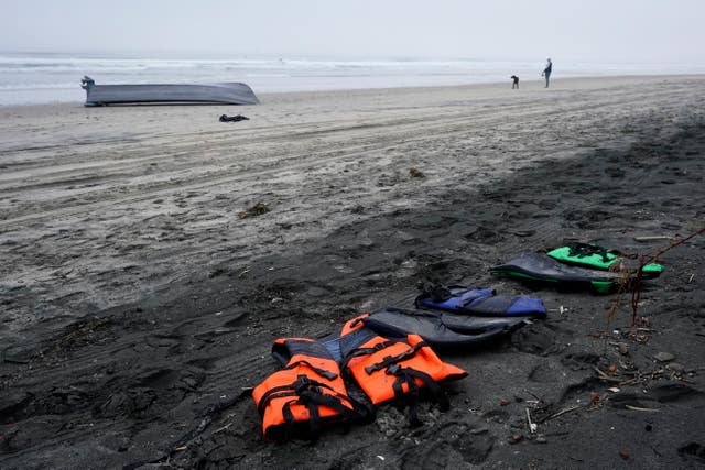 A boat sits overturned near a row of life jackets on Black's Beach in San Diego