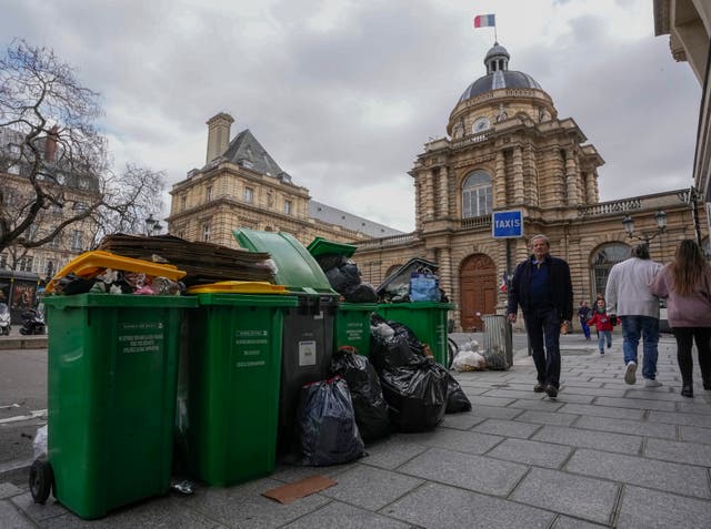 People walk past uncollected rubbish bins next to the Senate in Paris 