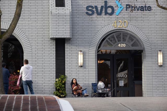 Jessika Harville, centre, and Michele Barry, right, wait for the Silicon Valley Bank to open in Palo Alto, California