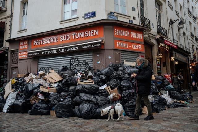 A man walks past piles of rubbish in Paris