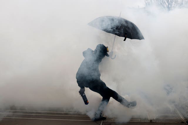 A protester kicks a teargas canister as he clashes with police during a demonstration in Nantes, western France