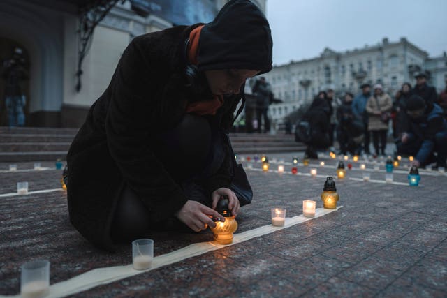 People light candles during a peaceful action to honour the memory of those killed in the Mariupol drama theatre a year ago, in Kyiv, Ukraine