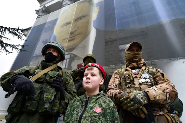 A boy and Russian soldiers take part in an event to mark the ninth anniversary of the Crimea annexation from Ukraine in Yalta, Crimea