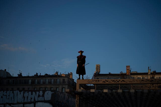 A man in costume stands over la Plaine during Marseille’s Carnaval de la Plaine in Marseille, southern France