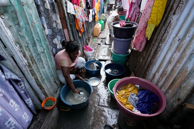 A woman washes utensils outside her house in Mumbai, India 