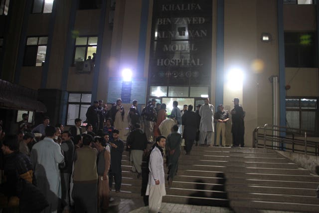 Police officers and people gather at a hospital where earthquake victims are brought