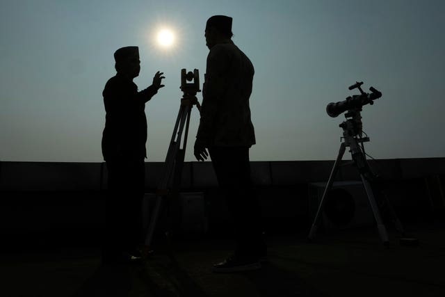 Officials are silhouetted as they use a telescope to scan the horizon for a crescent moon that will determine the beginning of Ramadan in Jakarta, Indonesia 