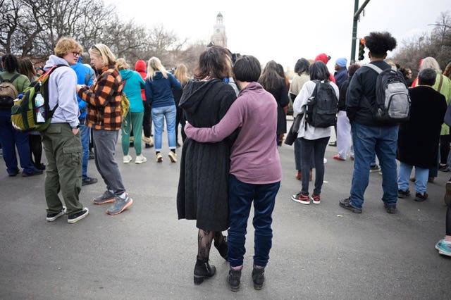 Isabella DeJoseph, 15, centre left, is embraced by her mother Alana as they leave East High School after a shooting there