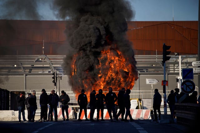 Dock workers stand in front of a burning barricade next to the port of Marseille in southern France 