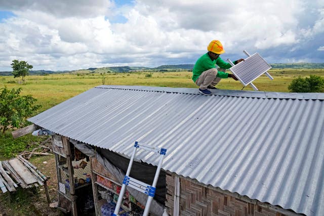 Antonius Makambombu, a worker of Sumba Sustainable Solutions, performs maintenance work on a solar panel on the roof of a customer’s shop in Laindeha village on Sumba Island, Indonesia