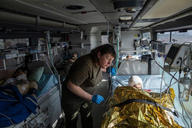 An injured Ukrainian soldier speaks to a volunteer from the Hospitallers paramedic organisation inside a special medical bus during the evacuation in Donetsk region