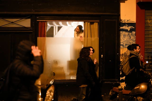 A woman watches through a window as protesters march in Paris on Wednesday