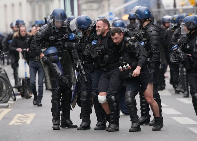 An injured police officer is taken away by his colleagues during a rally in Paris