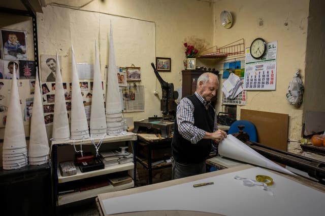 Jose Arenas adjusts a hood used by penitents during Holy Week processions at the Capirotes Arenas shop in Cordoba, southern Spain