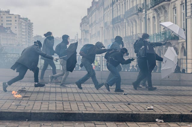 Protesters shield with umbrellas as they scuffle with riot police during a rally in Nantes