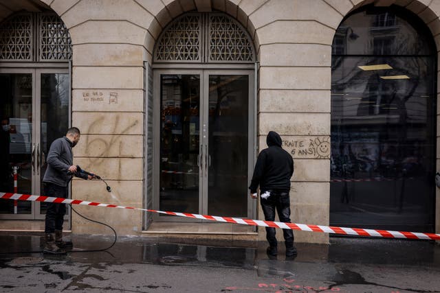 Council workers clean the wall of graffiti daubed during protests