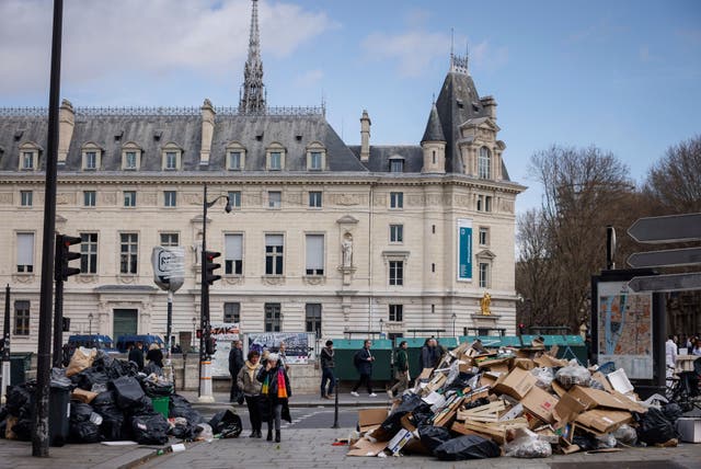 A man walks between uncollected rubbish piles in Paris on Friday