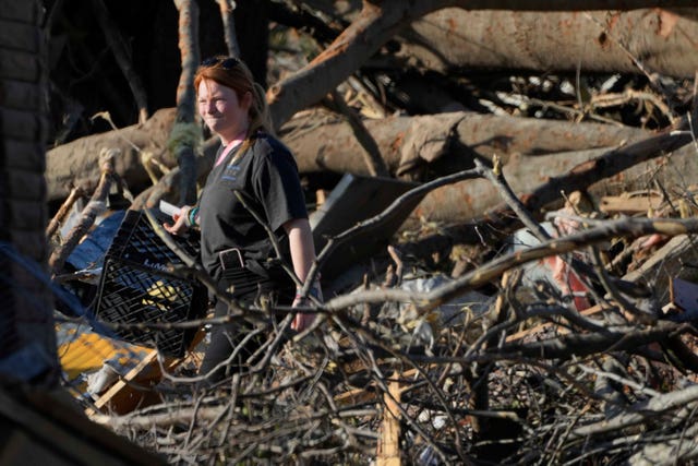 A Rolling Fork resident walks through fallen trees as she tries to salvage personal items following the tornado 