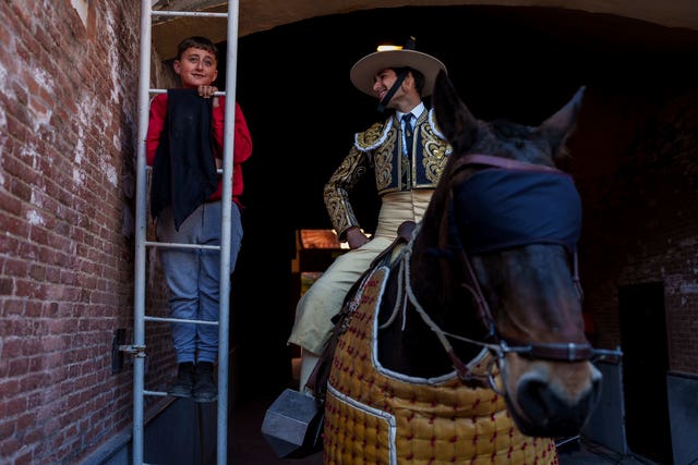 A child watches a bullfight next to a picador, a horse mounted bullfighter assistant, at Las Ventas bullring in Madrid, Spain